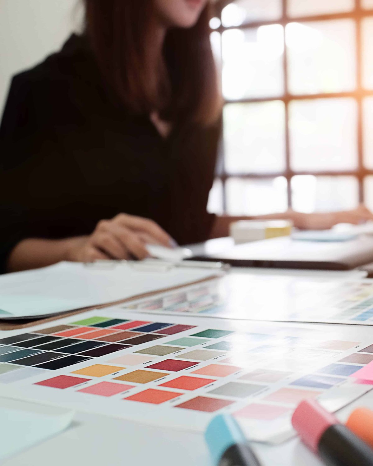 Designer at a desk with colour charts, markers and drafts